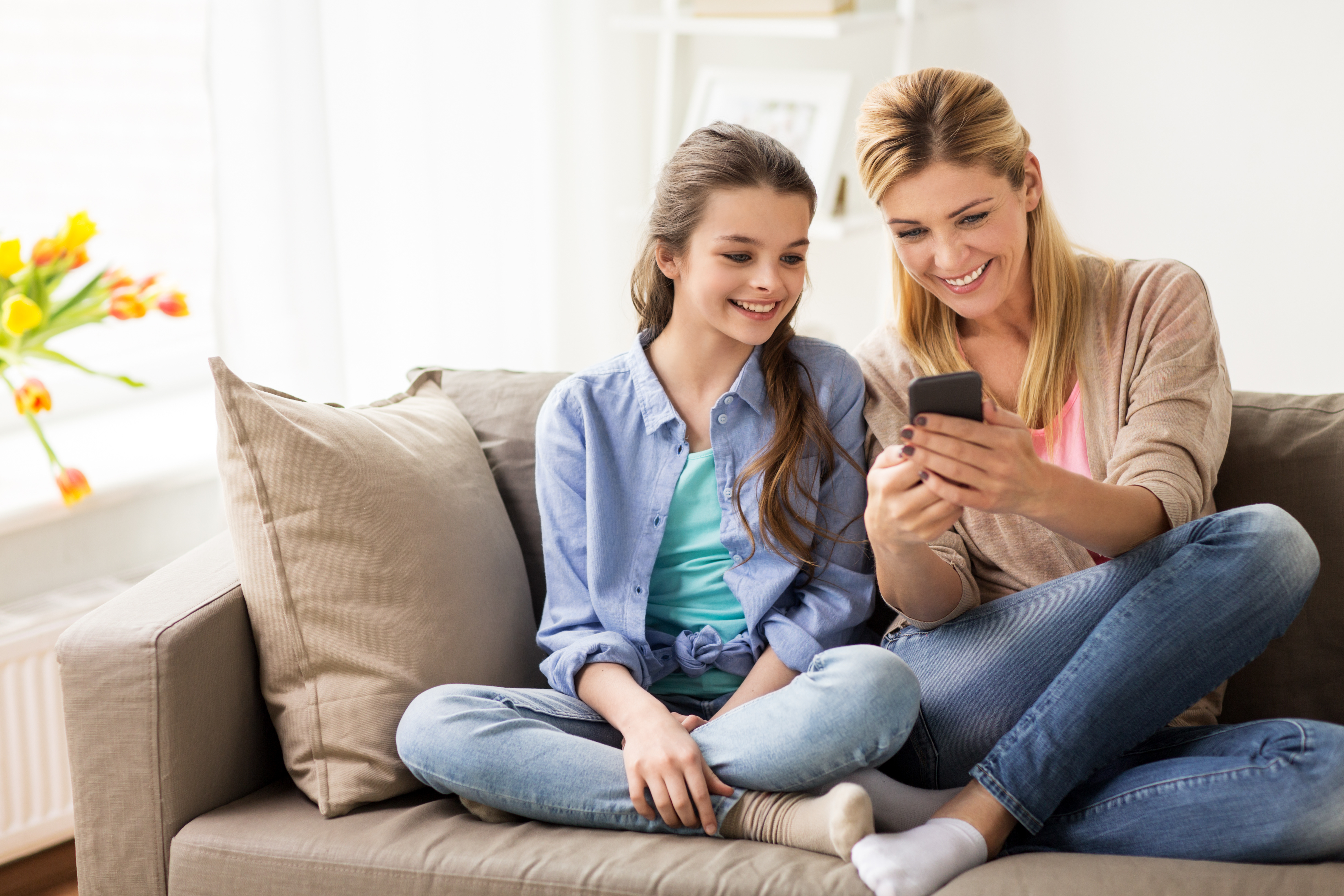 Stock photograph of a mother and daughter looking at a phone together